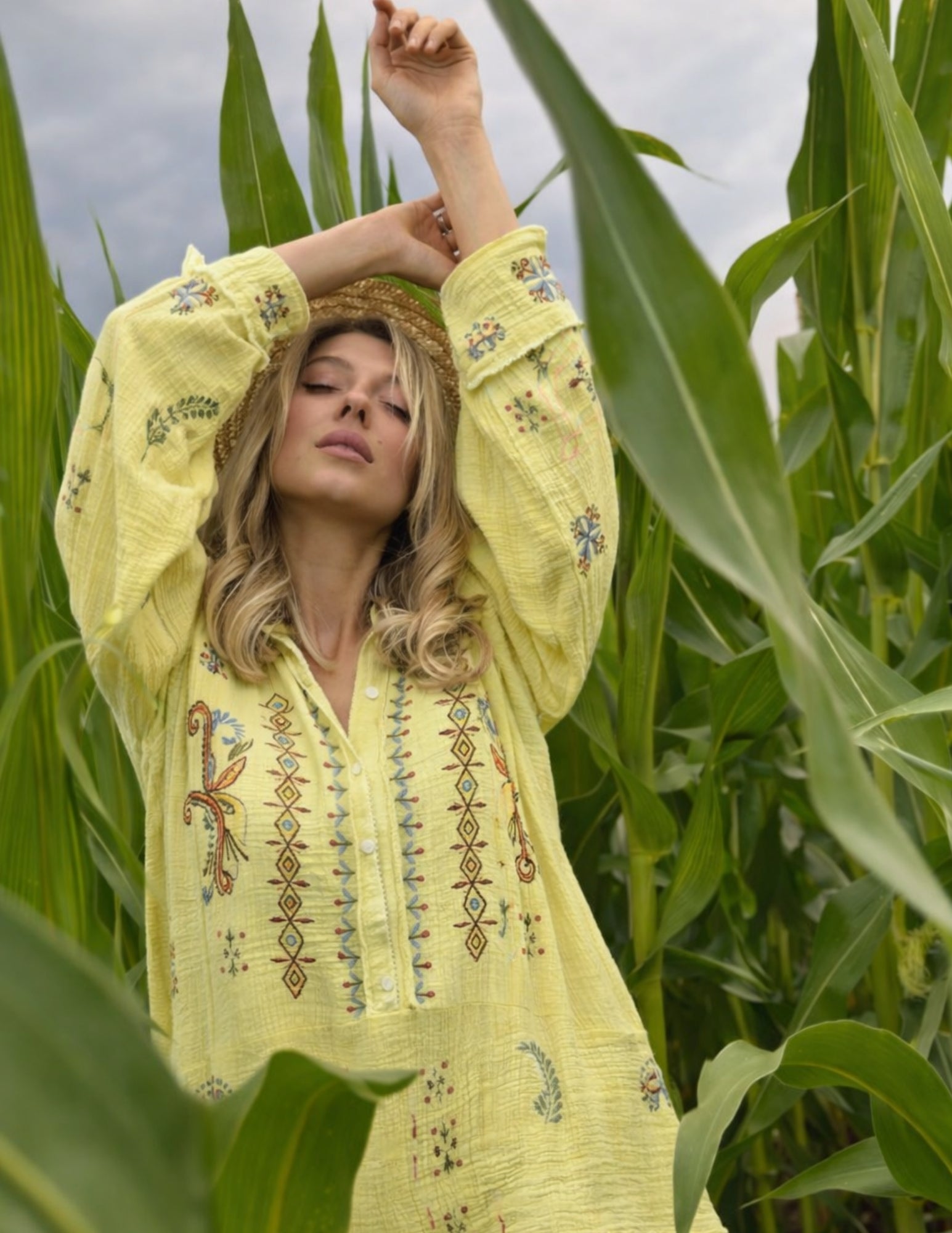 Woman in a yellow embroidered dress standing in a cornfield